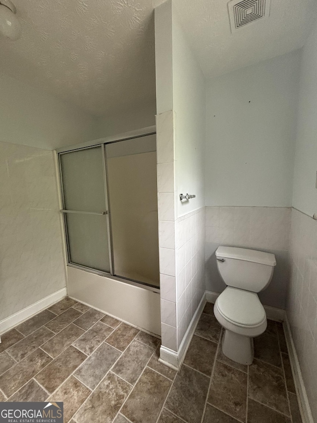 4069 Savannah Ridge Ct, Loganville, GA 30052 - bathroom with toilet, enclosed tub / shower combo, a textured ceiling, and wainscoting