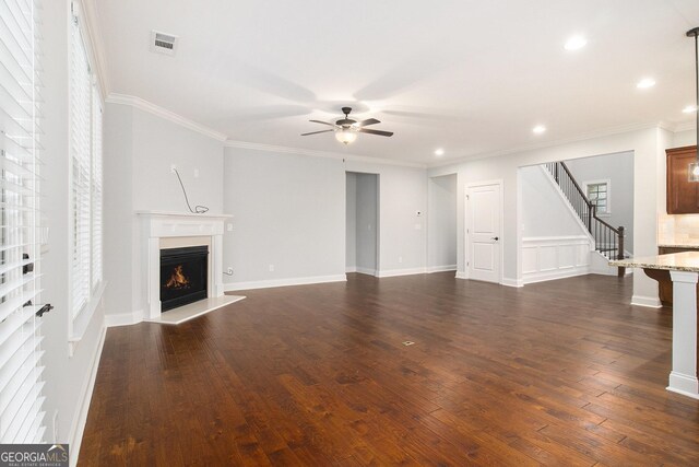 7139 Lake Edge Dr, Flowery Branch, GA 30542 - unfurnished living room with ceiling fan, a warm lit fireplace, ornamental molding, dark wood-style floors, and stairway