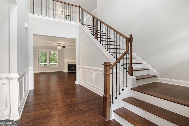7139 Lake Edge Dr, Flowery Branch, GA 30542 - stairway with a ceiling fan, wood finished floors, a lit fireplace, and a towering ceiling