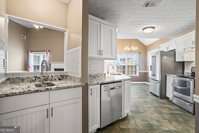 15 Livingston Way, Covington, GA 30016 - kitchen with stainless steel appliances, a sink, lofted ceiling, tasteful backsplash, and white cabinetry