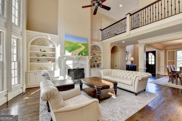 10125 Brixton Pl, Suwanee, GA 30024 - living room with a towering ceiling, a fireplace, a ceiling fan, ornamental molding, and dark wood finished floors