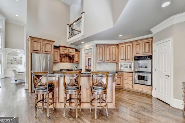 10125 Brixton Pl, Suwanee, GA 30024 - kitchen featuring stainless steel appliances, crown molding, a kitchen bar, light wood-style floors, and backsplash