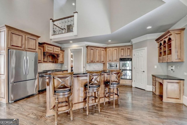 10125 Brixton Pl, Suwanee, GA 30024 - kitchen with appliances with stainless steel finishes, dark countertops, a breakfast bar, backsplash, and light wood-style floors