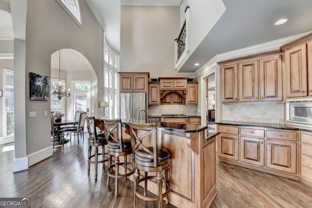 10125 Brixton Pl, Suwanee, GA 30024 - kitchen featuring stainless steel appliances, a breakfast bar area, light wood-type flooring, crown molding, and a high ceiling