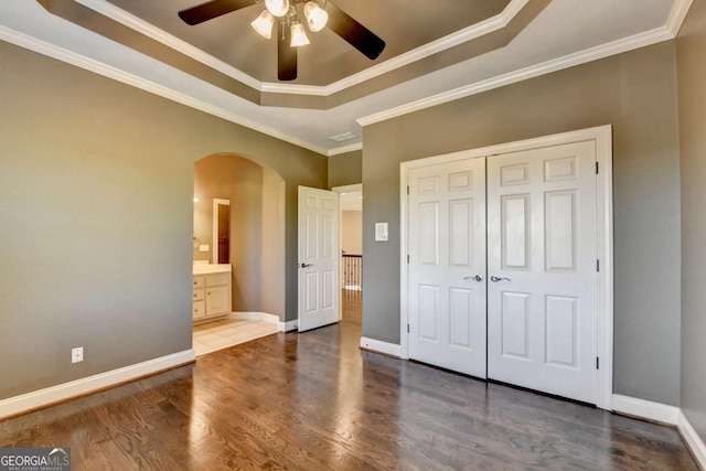 10125 Brixton Pl, Suwanee, GA 30024 - unfurnished bedroom with arched walkways, a raised ceiling, wood finished floors, baseboards, and ornamental molding
