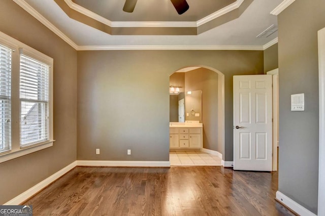 10125 Brixton Pl, Suwanee, GA 30024 - spare room featuring a tray ceiling, arched walkways, healthy amount of natural light, wood finished floors, and ornamental molding