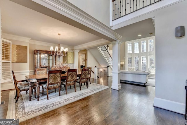 10125 Brixton Pl, Suwanee, GA 30024 - dining room with wood finished floors, crown molding, a chandelier, a high ceiling, and stairs