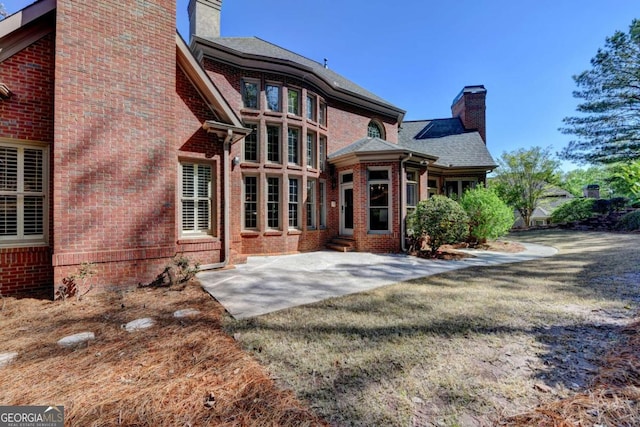 10125 Brixton Pl, Suwanee, GA 30024 - back of property featuring a chimney, brick siding, and a patio