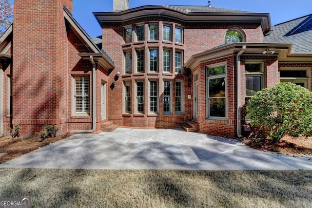 10125 Brixton Pl, Suwanee, GA 30024 - back of property with a chimney, brick siding, entry steps, and a patio area