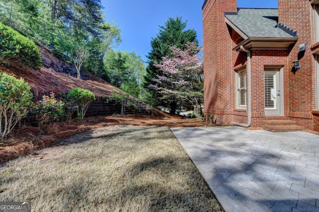 10125 Brixton Pl, Suwanee, GA 30024 - view of side of home with a chimney, a patio area, a shingled roof, brick siding, and entry steps