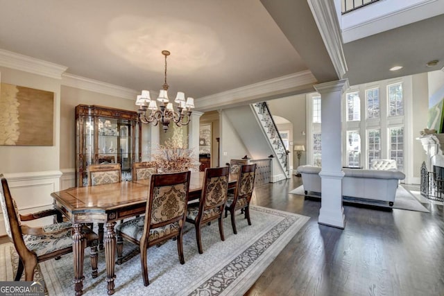 10125 Brixton Pl, Suwanee, GA 30024 - dining space featuring a chandelier, dark wood finished floors, crown molding, stairs, and ornate columns