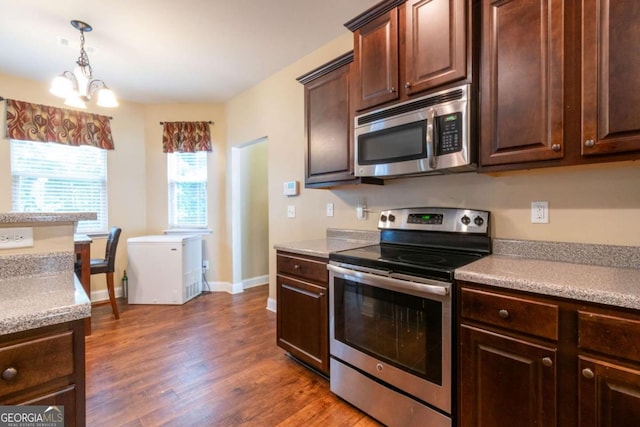 12275 Styron Dr, Hampton, GA 30228 - kitchen with appliances with stainless steel finishes, dark brown cabinets, dark wood-type flooring, a chandelier, and light countertops