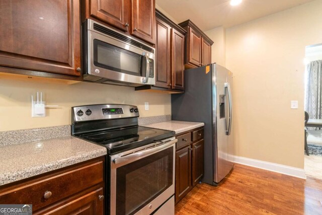 12275 Styron Dr, Hampton, GA 30228 - kitchen with appliances with stainless steel finishes, light wood-style floors, dark brown cabinets, and recessed lighting