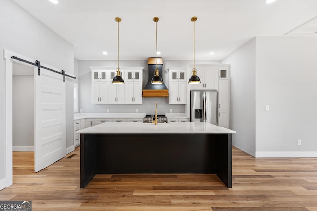 182 Cherry Rose Ln, Hartwell, GA 30643 - kitchen featuring appliances with stainless steel finishes, a barn door, premium range hood, light countertops, and a kitchen island with sink