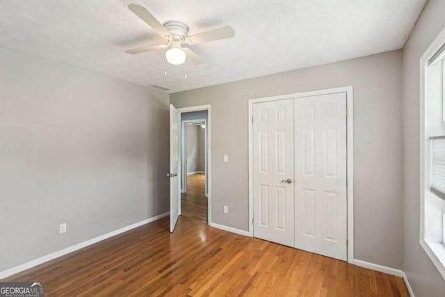 2201 Colonial Oak Way, Stone Mountain, GA 30087 - unfurnished bedroom with wood finished floors, baseboards, a closet, and a ceiling fan