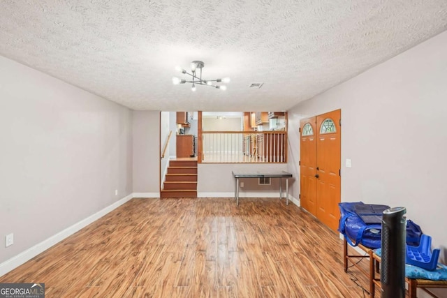 2201 Colonial Oak Way, Stone Mountain, GA 30087 - unfurnished living room with wood finished floors, stairway, a chandelier, baseboards, and a textured ceiling