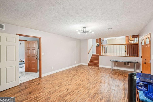 2201 Colonial Oak Way, Stone Mountain, GA 30087 - unfurnished living room with wood finished floors, stairway, a chandelier, a textured ceiling, and baseboards