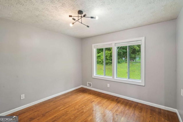 2201 Colonial Oak Way, Stone Mountain, GA 30087 - unfurnished room with hardwood / wood-style floors, baseboards, a textured ceiling, and a chandelier