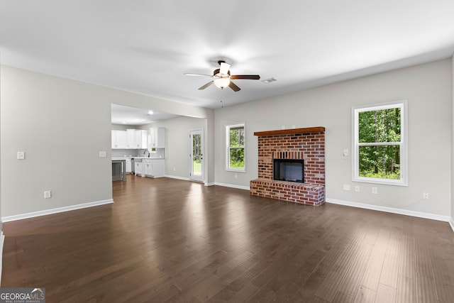 74 Riverwood Trl, Grantville, GA 30220 - unfurnished living room featuring a ceiling fan, a brick fireplace, healthy amount of natural light, and baseboards
