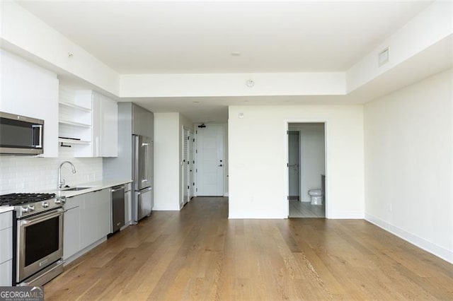 788 Marietta St Unit 311, Atlanta, GA 30318 - kitchen featuring stainless steel appliances, open shelves, light countertops, tasteful backsplash, and light wood-style floors