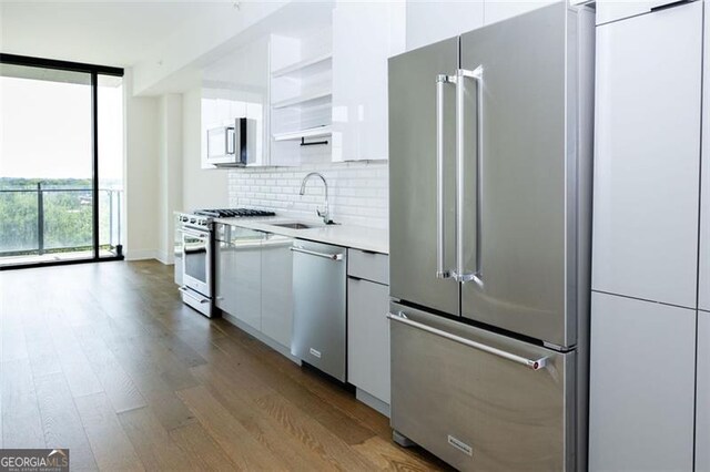 788 Marietta St Unit 311, Atlanta, GA 30318 - kitchen featuring premium appliances, wood finished floors, light countertops, decorative backsplash, and white cabinetry