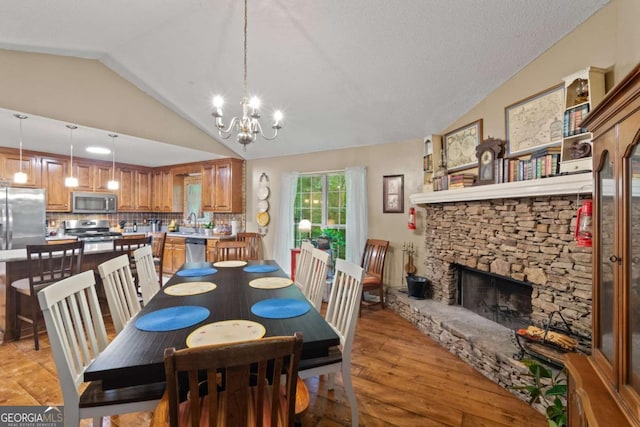 345 Jesse Martin Trl, Canton, GA 30115 - dining room with vaulted ceiling, a chandelier, light wood-style flooring, and a stone fireplace