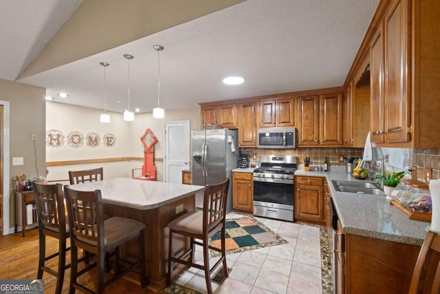 345 Jesse Martin Trl, Canton, GA 30115 - kitchen with stainless steel appliances, brown cabinetry, decorative backsplash, a breakfast bar, and hanging light fixtures