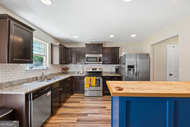 149 Pristine Dr, Locust Grove, GA 30248 - kitchen with appliances with stainless steel finishes, light wood-style flooring, dark brown cabinets, butcher block counters, and recessed lighting