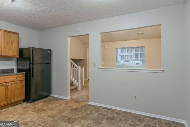 4634 Garden Hills Dr, Stone Mountain, GA 30083 - kitchen featuring freestanding refrigerator, brown cabinetry, a textured ceiling, and dark countertops
