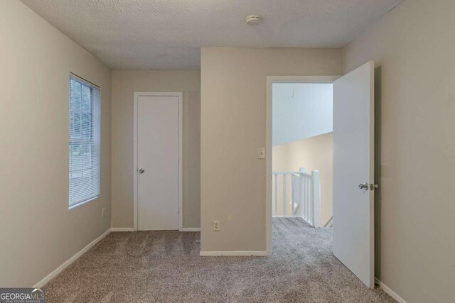 4634 Garden Hills Dr, Stone Mountain, GA 30083 - unfurnished bedroom with multiple windows, carpet, and a textured ceiling