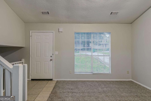 4634 Garden Hills Dr, Stone Mountain, GA 30083 - entryway featuring a textured ceiling, light tile patterned flooring, and light colored carpet