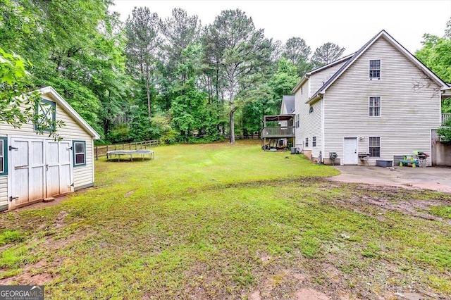 2200 E Lake Rd, Mcdonough, GA 30252 - view of green lawn with a trampoline, a patio area, view of scattered trees, and a wooden deck