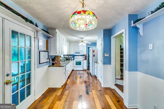 2200 E Lake Rd, Mcdonough, GA 30252 - kitchen featuring white appliances, a textured ceiling, dark countertops, white cabinetry, and hardwood / wood-style flooring