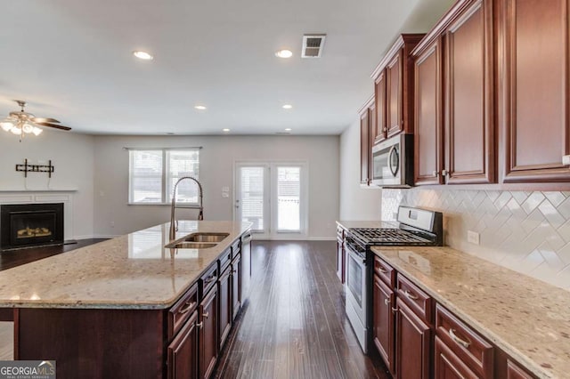 385 Broadmoor Dr, Braselton, GA 30517 - kitchen featuring stainless steel appliances, a sink, ceiling fan, decorative backsplash, and a fireplace with flush hearth