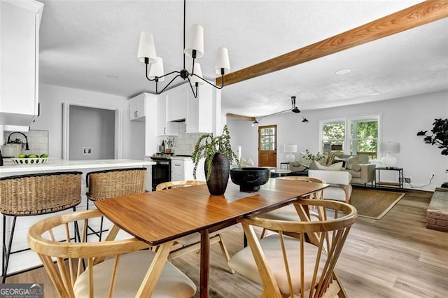 5666 Fawn Dr, Powder Springs, GA 30127 - dining space with light wood-type flooring, a chandelier, and beam ceiling