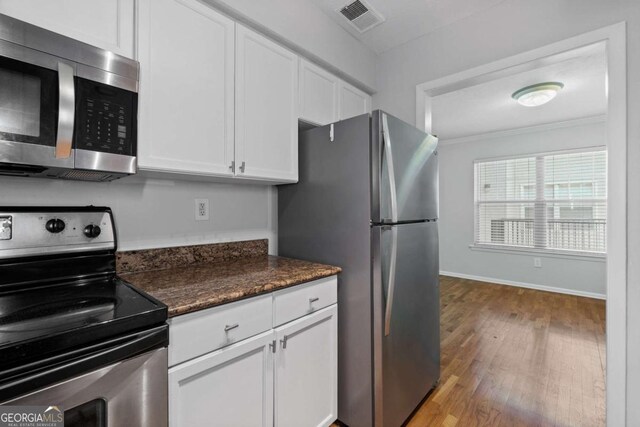 1150 Collier Rd NW Unit 6H, Atlanta, GA 30318 - kitchen featuring appliances with stainless steel finishes, a sink, light wood-type flooring, dark stone countertops, and white cabinets
