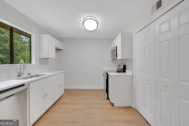 112 Valley Rd, Stockbridge, GA 30281 - kitchen with stainless steel appliances, a sink, light wood-style flooring, light countertops, and white cabinetry