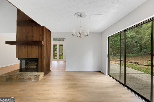 112 Valley Rd, Stockbridge, GA 30281 - unfurnished dining area featuring light wood-style flooring, a chandelier, baseboards, and a large fireplace