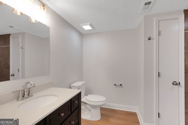 112 Valley Rd, Stockbridge, GA 30281 - bathroom with vanity, wood finished floors, toilet, a textured ceiling, and baseboards