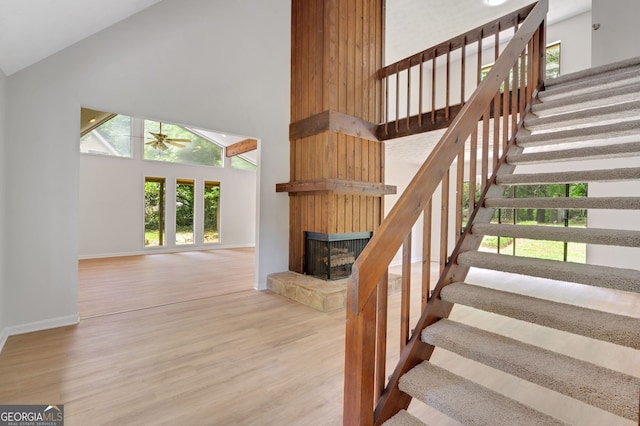 112 Valley Rd, Stockbridge, GA 30281 - stairs featuring high vaulted ceiling, a fireplace with raised hearth, wood finished floors, baseboards, and a ceiling fan