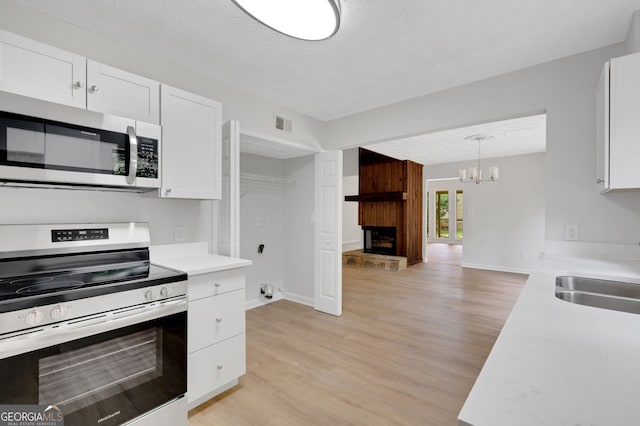 112 Valley Rd, Stockbridge, GA 30281 - kitchen featuring stainless steel appliances, light wood finished floors, a sink, light countertops, and white cabinets