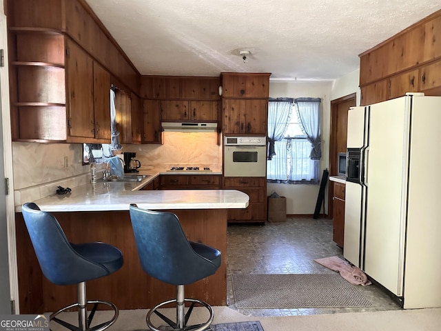 984 Morrow Rd, Morrow, GA 30260 - kitchen featuring white fridge with ice dispenser, oven, under cabinet range hood, a sink, and a peninsula
