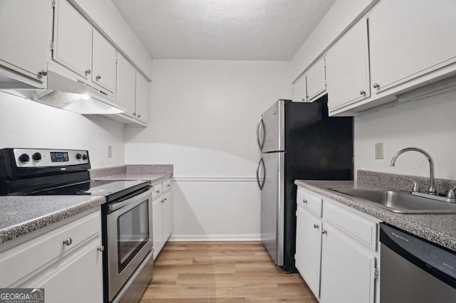 5157 Roswell Rd Unit 1, Atlanta, GA 30342 - kitchen featuring appliances with stainless steel finishes, a sink, white cabinets, light wood-type flooring, and a textured ceiling