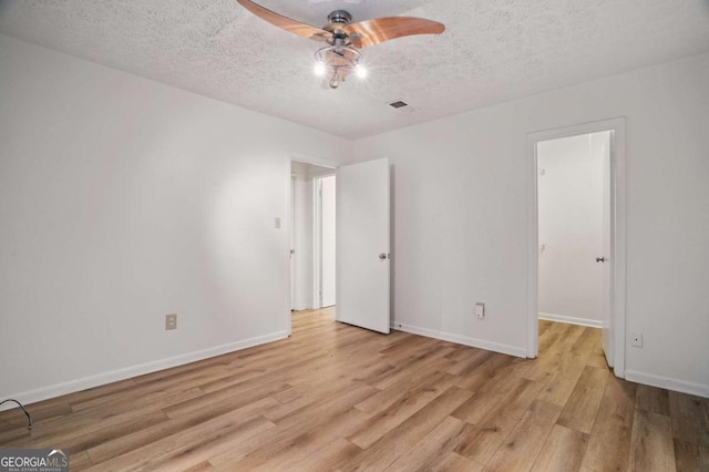 5157 Roswell Rd Unit 1, Atlanta, GA 30342 - unfurnished bedroom with light wood-style flooring, a textured ceiling, baseboards, ceiling fan, and a walk in closet