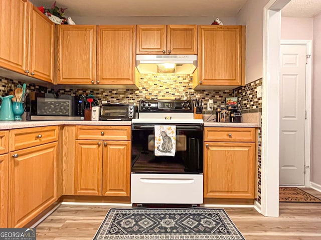 6830 Peeksville Rd, Mcdonough, GA 30252 - kitchen featuring under cabinet range hood, electric range, light wood-style floors, decorative backsplash, and light countertops