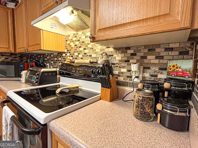 6830 Peeksville Rd, Mcdonough, GA 30252 - kitchen with electric range, under cabinet range hood, decorative backsplash, light countertops, and black microwave