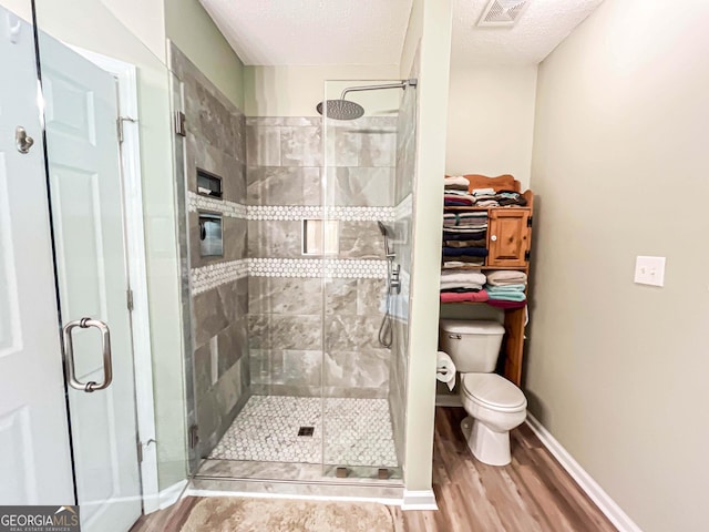6830 Peeksville Rd, Mcdonough, GA 30252 - bathroom with toilet, wood finished floors, a stall shower, and a textured ceiling