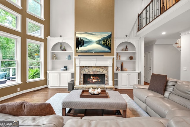 702 Crescent Cir, Canton, GA 30115 - living room featuring a towering ceiling, healthy amount of natural light, wood finished floors, a stone fireplace, and built in shelves