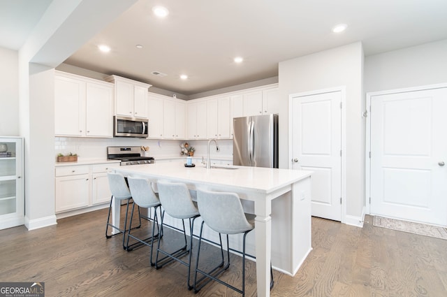 831 Corsiglia Farm Flts, Marietta, GA 30060 - kitchen with appliances with stainless steel finishes, a sink, dark wood-style flooring, a center island with sink, and white cabinetry