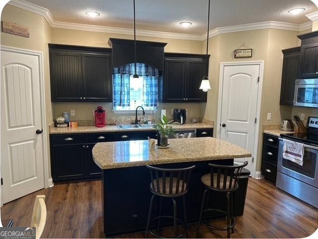 4961 Bentwood Ct, Valdosta, GA 31601 - kitchen with appliances with stainless steel finishes, a sink, a center island, dark wood-style flooring, and crown molding